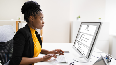 A woman sits in front of her computer, using AI to craft her resume.
