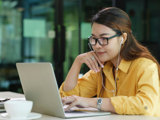 Woman on laptop using ear buds